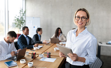 Karriere Frau steht vor einer Gruppe Menschen und hält iPad in der Hand